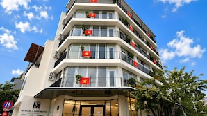 Ein mehrstöckiges Hotel mit Balkonen, die jeweils mit einer Flagge geschmückt sind.