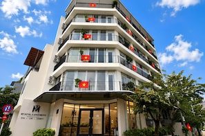 Un hotel de varios pisos con balcones, cada uno decorado con una bandera.