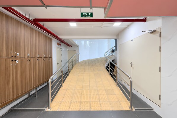 A corridor with lockers, a tactile paving path, and an exit sign. - MT Danang Hotel - Near Dragon Bridge (An Hai)