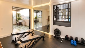 Ein modernes Fitnessstudio mit Trainingsgeräten, einem großen Spiegel und Blick auf die Stadt durch ein Fenster.