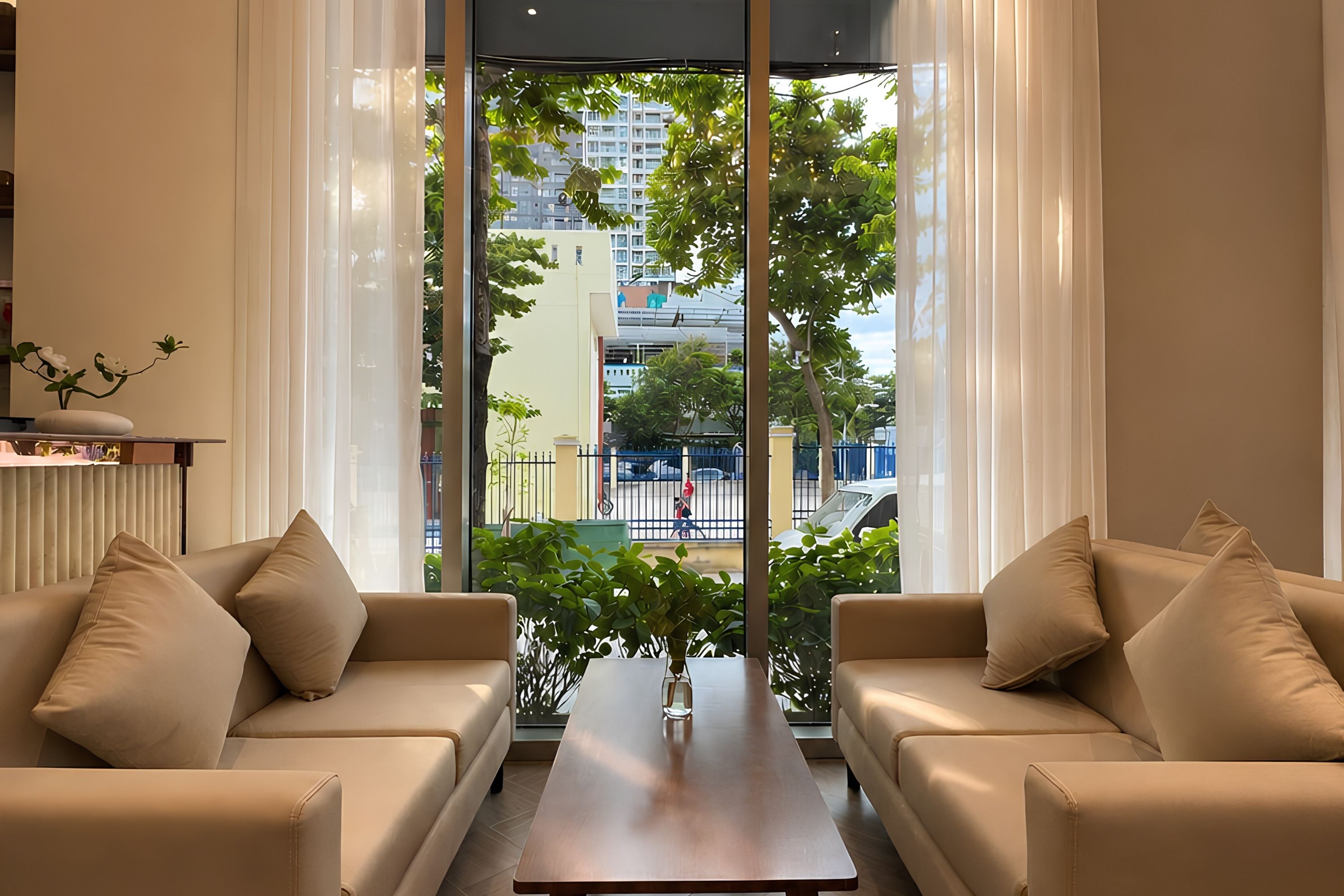 A modern living room with two sofas, a coffee table, and a view of a cityscape through large windows.