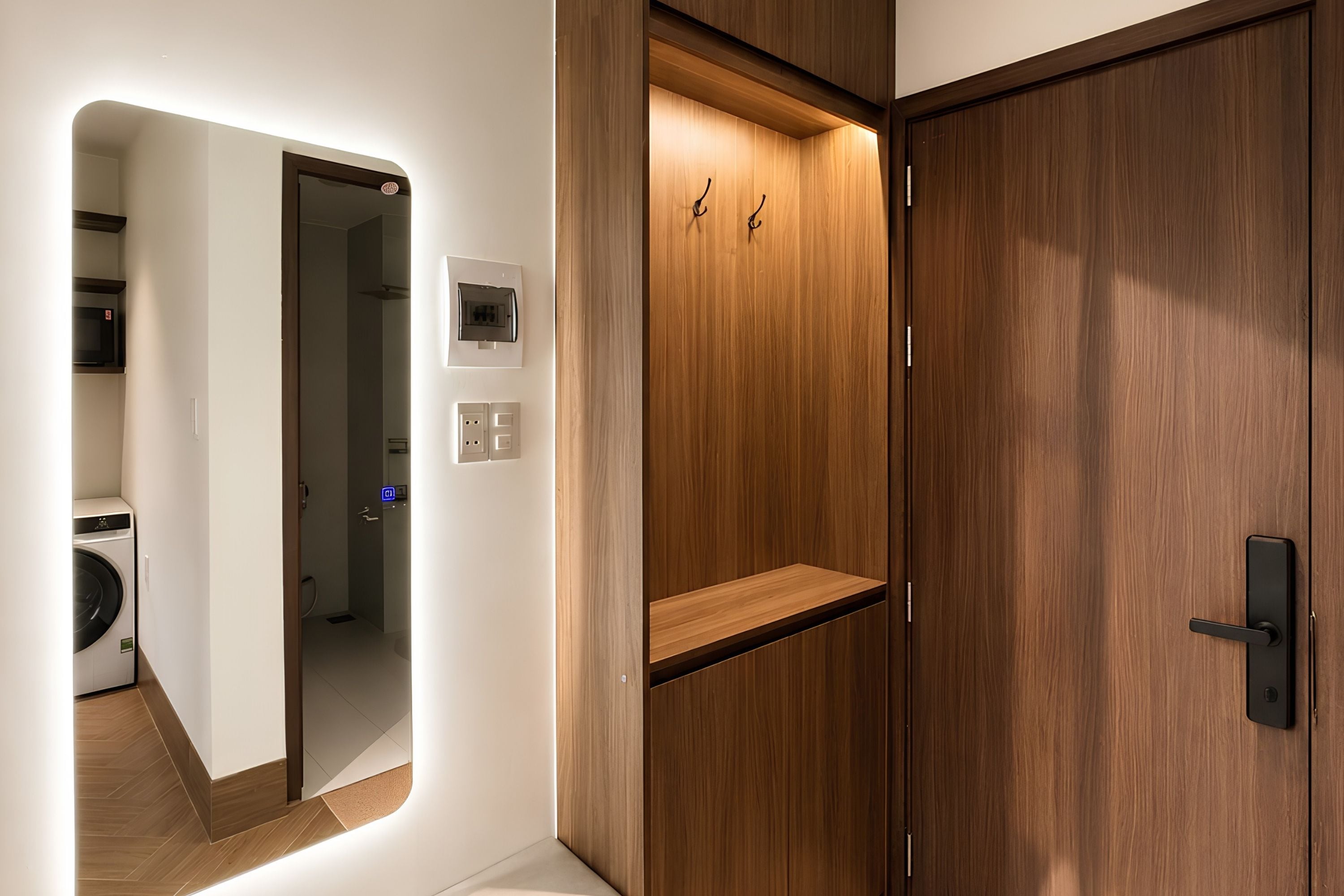 A hotel room with a wooden wardrobe, a mirror, and a built-in washing machine.