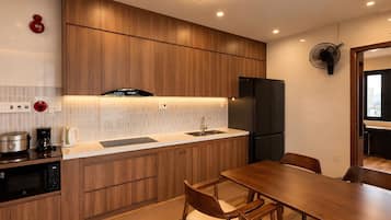 Una cocina moderna con armarios de madera, horno empotrado, un lavamanos y una zona de comedor con mesa y sillas.