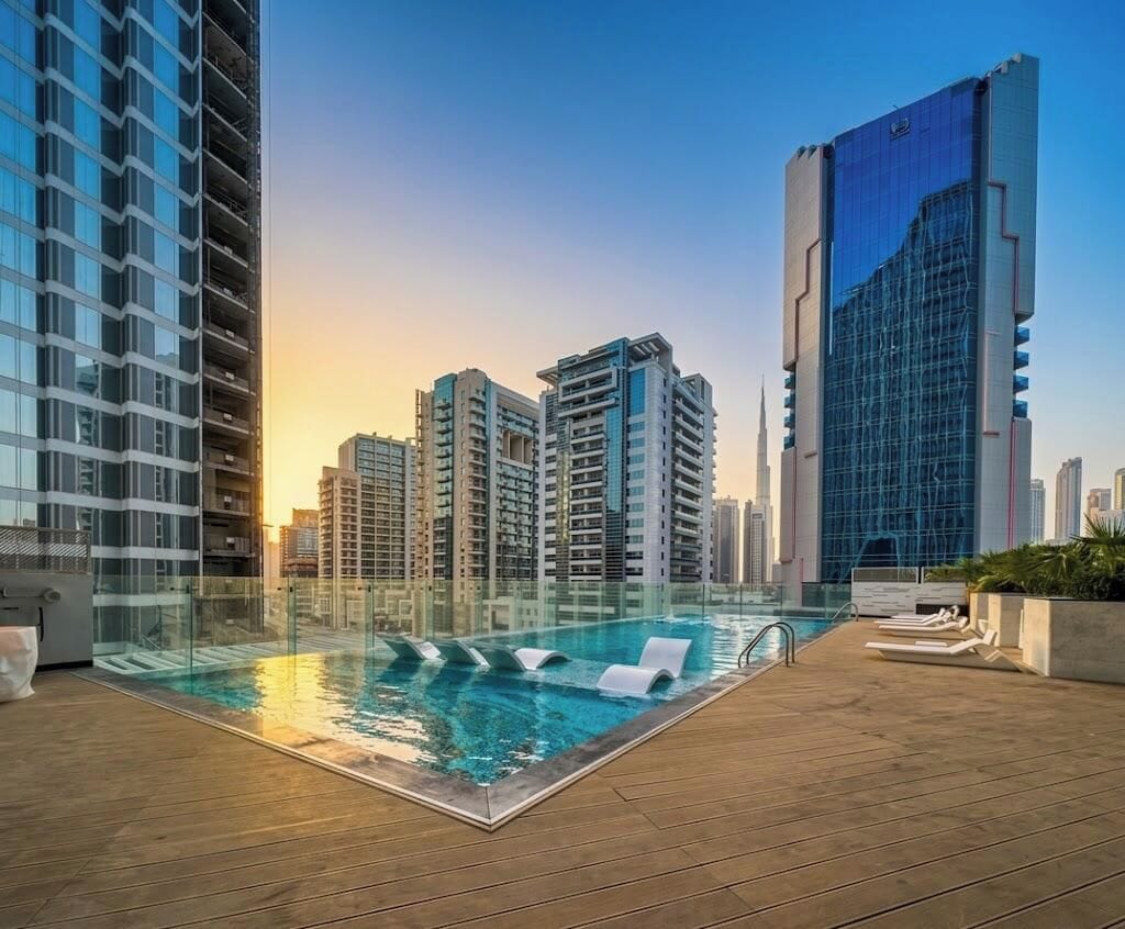 A rooftop pool with a view of high-rise buildings, including a distinctive building with a blue facade.