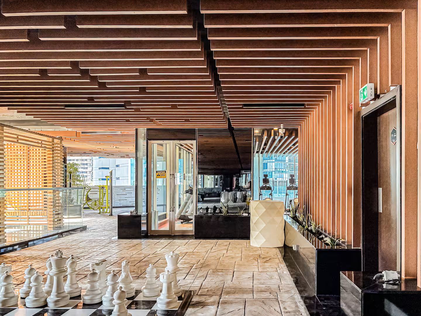 Um saguão com um tabuleiro de xadrez, divisória de vidro e design de interiores moderno.