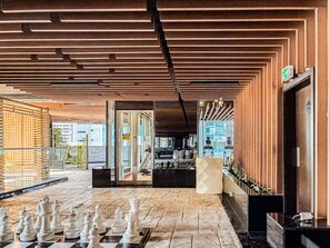 Um saguão com um tabuleiro de xadrez, divisória de vidro e design de interiores moderno.