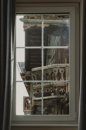 A window with a view of a wooden balcony with intricate carvings.