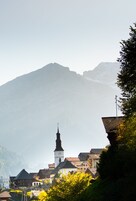 Una montaña con la aguja de una iglesia al frente.