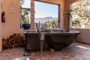 A hot tub with a view of mountains, a fire extinguisher, and a stack of firewood.