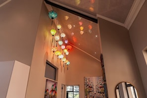 A room with a ceiling adorned with hanging lanterns, a large window, and a painting on the wall.