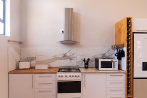 A modern kitchen with a gas stove, oven, microwave, and a built-in wine rack.
