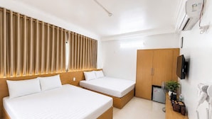 A hotel room with two beds, a wooden wardrobe, a desk with a phone and a hairdryer, and a small plant. - Cat Ba Thai Long Hotel (Cat Hai)