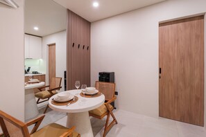 A dining area with a round table, chairs, and a kitchen in the background. - Tranquil 24 Villa by Betterplace (Pecatu)