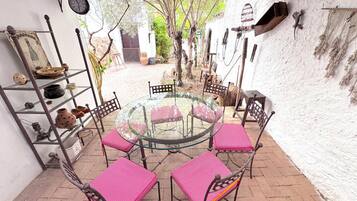 Une table ronde en verre, entourée de quatre chaises, et un patio pavé de briques.