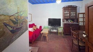 Una sala de estar con un sofá rojo, un televisor, un mueble de madera y un techo con vigas azules.