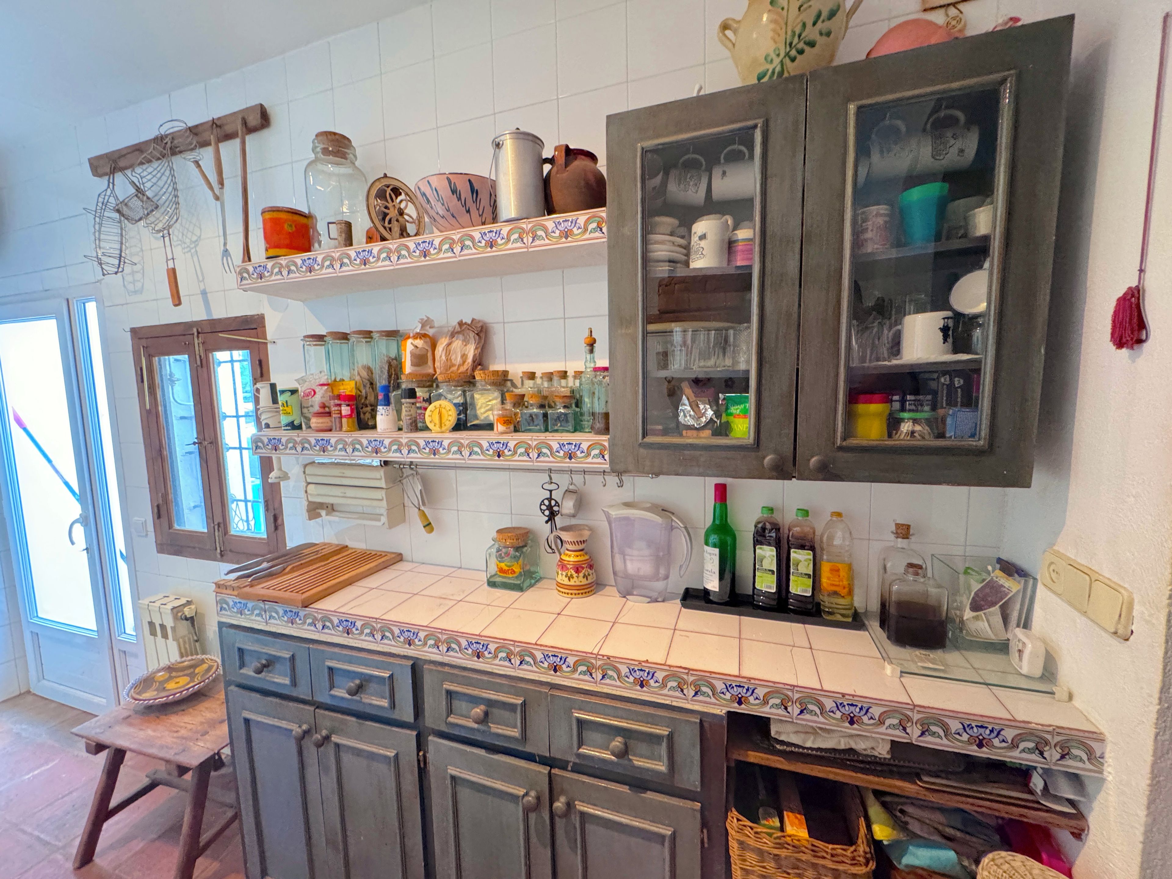Una cocina con salpicadero de azulejos, armarios de madera y diversos utensilios y electrodomésticos.