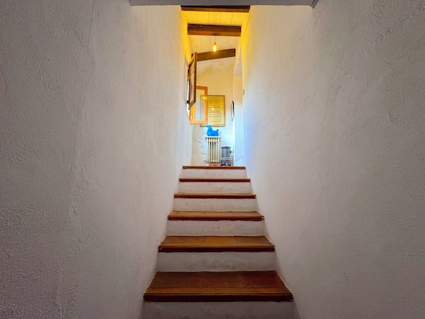 Una escalera que lleva a una habitación con un radiador y un objeto azul en la pared.
