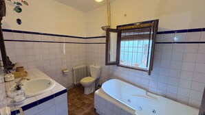 Un baño con bañera, inodoro, lavabo y ventana con vistas.