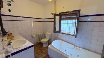 Une salle de bain équipée d’une baignoire, de toilettes, d’un lavabo et d’une fenêtre donnant sur un beau paysage.
