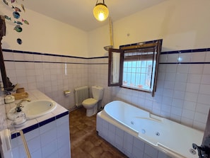Ein Badezimmer mit einer Badewanne, Toilette, Waschbecken und einem Fenster mit Blick.