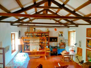 A rustic room with a sloped ceiling, a bed with a colorful bedspread, a desk with a chair, a bookshelf, and a small table with a chair. - RURAL HOUSE IN LA ALAMEDA DE CERVERA (Alameda de Cervera)
