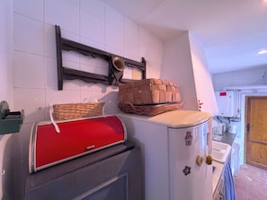 Una cocina con un electrodoméstico rojo, una cesta tejida y un refrigerador blanco.