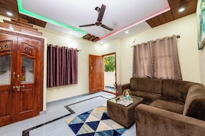 A living room with a sofa, a coffee table, a ceiling fan, and a patterned rug.