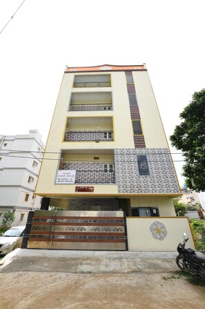 Un edificio de varios pisos con una fachada simétrica, balcones en cada nivel y una entrada con portones.