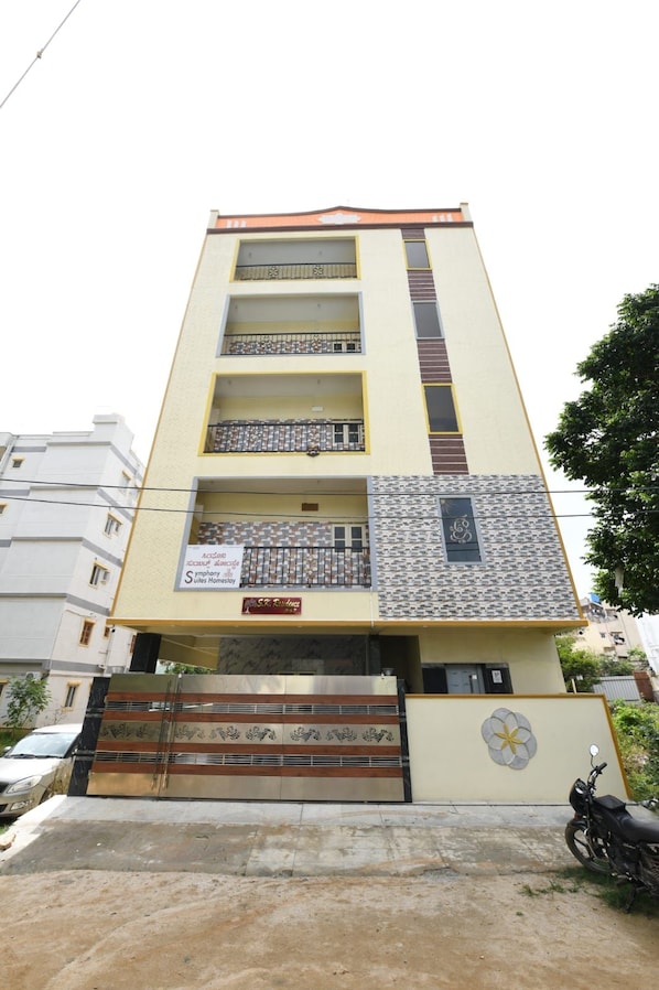 A multi-story building with a symmetrical facade, balconies on each floor, and a gated entrance.
