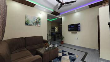 A modern living room with a brown sofa, a glass coffee table, and a painting on the wall.