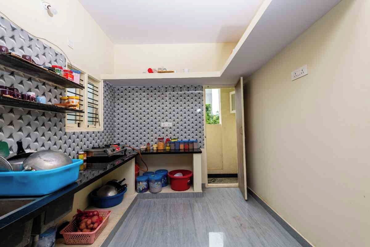 A compact kitchen with a grey textured wall, shelves with kitchenware, and a small countertop.