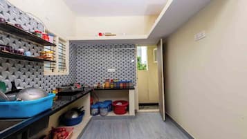 A compact kitchen with a grey textured wall, shelves with kitchenware, and a small countertop.
