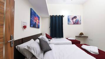 A hotel room with two beds, a red curtain, and artwork on the walls.