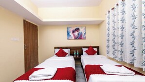 Habitación de hotel con dos camas, un cuadro en la pared y una ventana con cortinas.