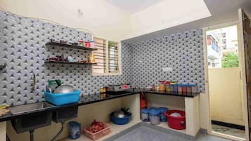 Una cocina compacta con cubierta negra, paneles de pared grises con textura y una ventana.