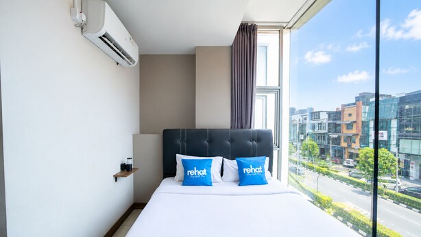 Quarto de hotel com uma cama grande, vista da cidade e ar condicionado na parede.