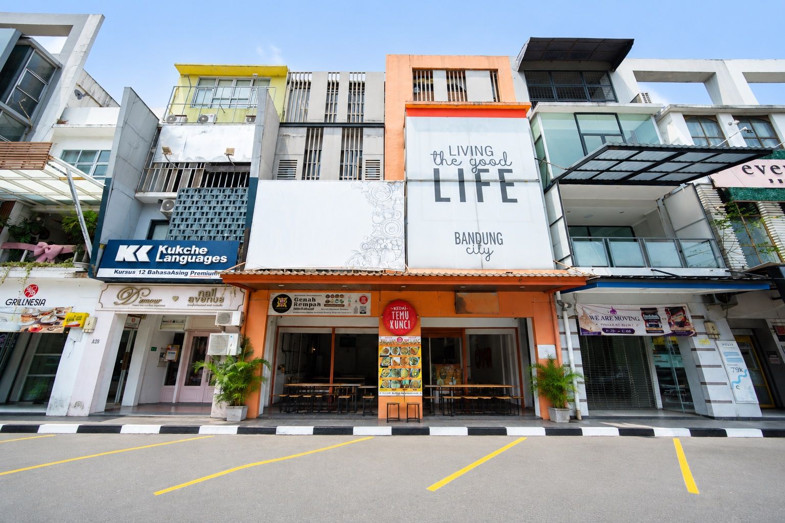 A multi-story commercial building with various storefronts, including a language school, a restaurant, and a moving company.