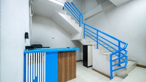 Uma receção com design azul e branco, uma escadaria com guardaílos azuis e um chão em mosaico.