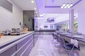 Une cuisine moderne dotée d’un long comptoir, d’appareils électroménagers en acier inoxydable et d’un coin repas avec une table et des chaises en marbre.