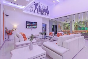 A modern living room with a large flat-screen TV, white sofas, and a glass coffee table. - Pratumnak Hill PoolVilla 4BR Luxury(PH2) (Banglamung)