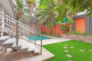 A pool area with a staircase leading to a building, surrounded by greenery and a stone wall. - Pratumnak Hill PoolVilla 4BR Luxury(PH2) (Banglamung)