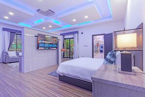 Une chambre moderne avec un lit, un téléviseur fixé au mur et une vue sur l’extérieur.