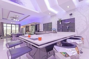 A modern kitchen with a central island, bar seating, and a dining area with a view. - Pratumnak Hill PoolVilla 4BR Luxury(PH2) (Banglamung)