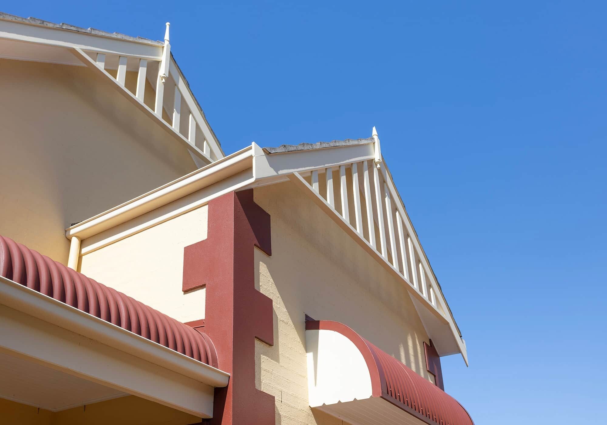 A building with a white facade, a red accent wall, and a balcony with white railings.