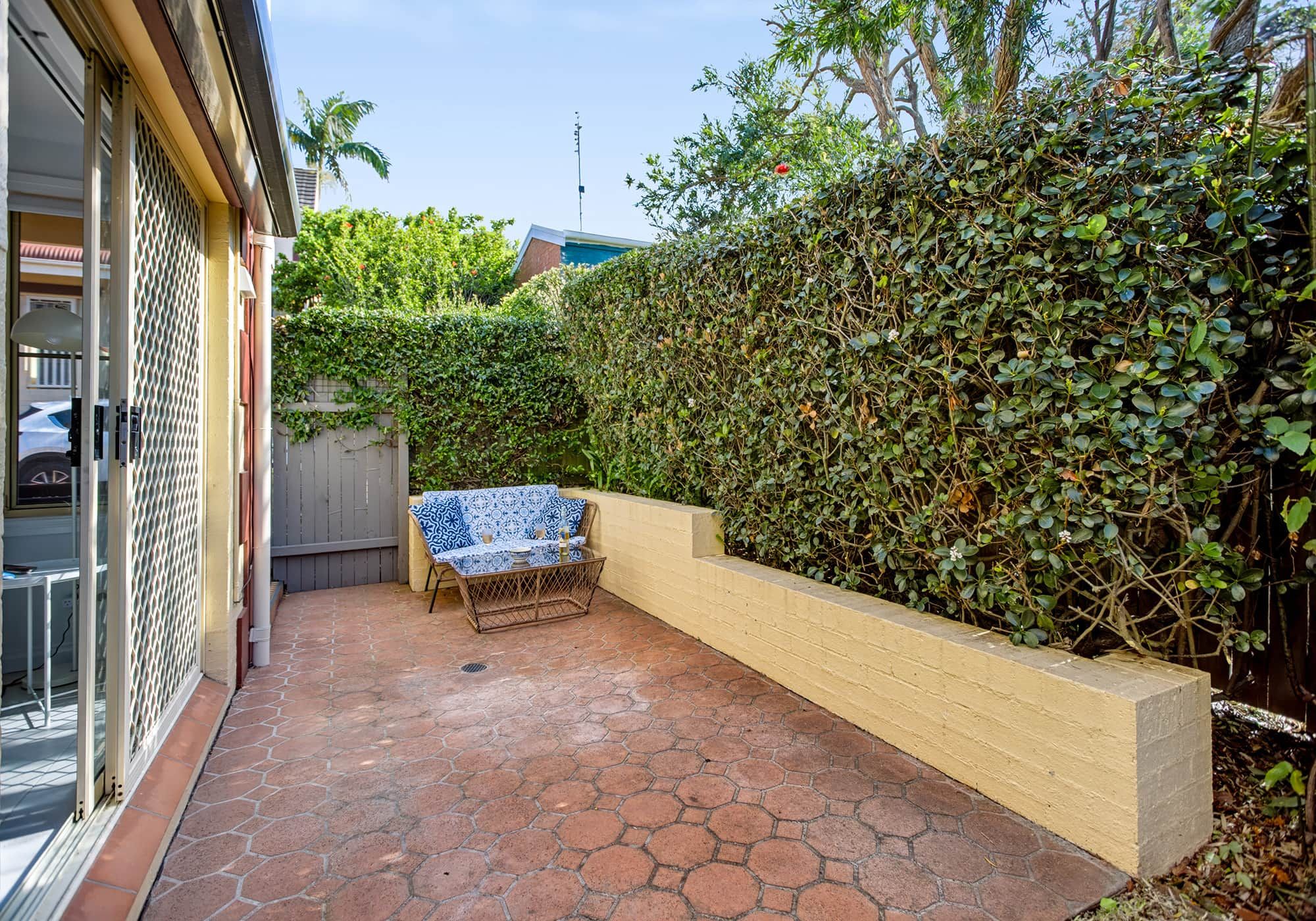 A patio area with a bench, a wall planter, and a tiled floor.