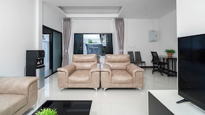 A modern living room with a sofa set, a flat-screen TV, and a water dispenser. - Elyana Haven | Luxury 3BR Private Pool Villa in Rawai, Phuket (Tambon Rawai)
