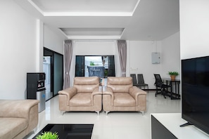 A modern living room with a sofa set, a flat-screen TV, and a water dispenser. - Elyana Haven | Luxury 3BR Private Pool Villa in Rawai, Phuket (Tambon Rawai)