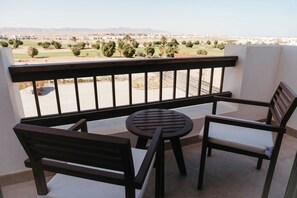 Un balcón con vistas a un campo de golf y montañas lejanas.