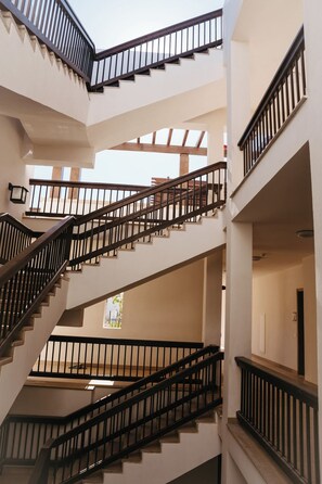 Un interior de diversos nivells amb una escala central, espais oberts i una vista per la finestra.