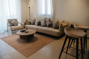 Una sala de estar moderna con un sofá, dos sillones, una mesa de centro y una lámpara de pie.